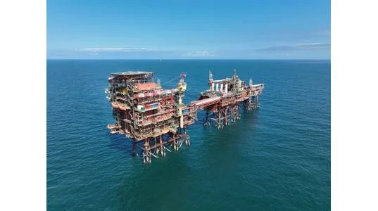 Rough offshore gas infrastructure standing above the sea, with interconnected platforms and access bridges.
