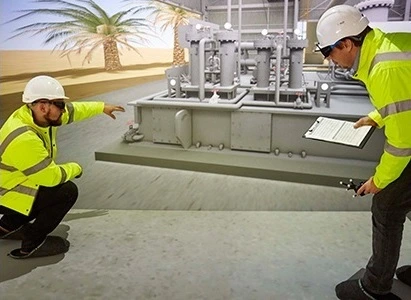 Two participants in hard hats and high-visibility jackets interacting with the TSC virtual plant training system in an EON Icube.