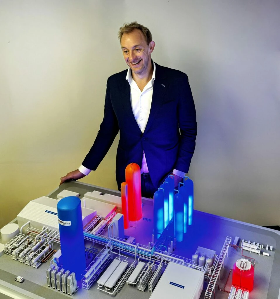 Richard Butland standing behind an illuminated physical scale model of the Highview Power CRYOBattery plant, with storage vessels, buildings and pipework.